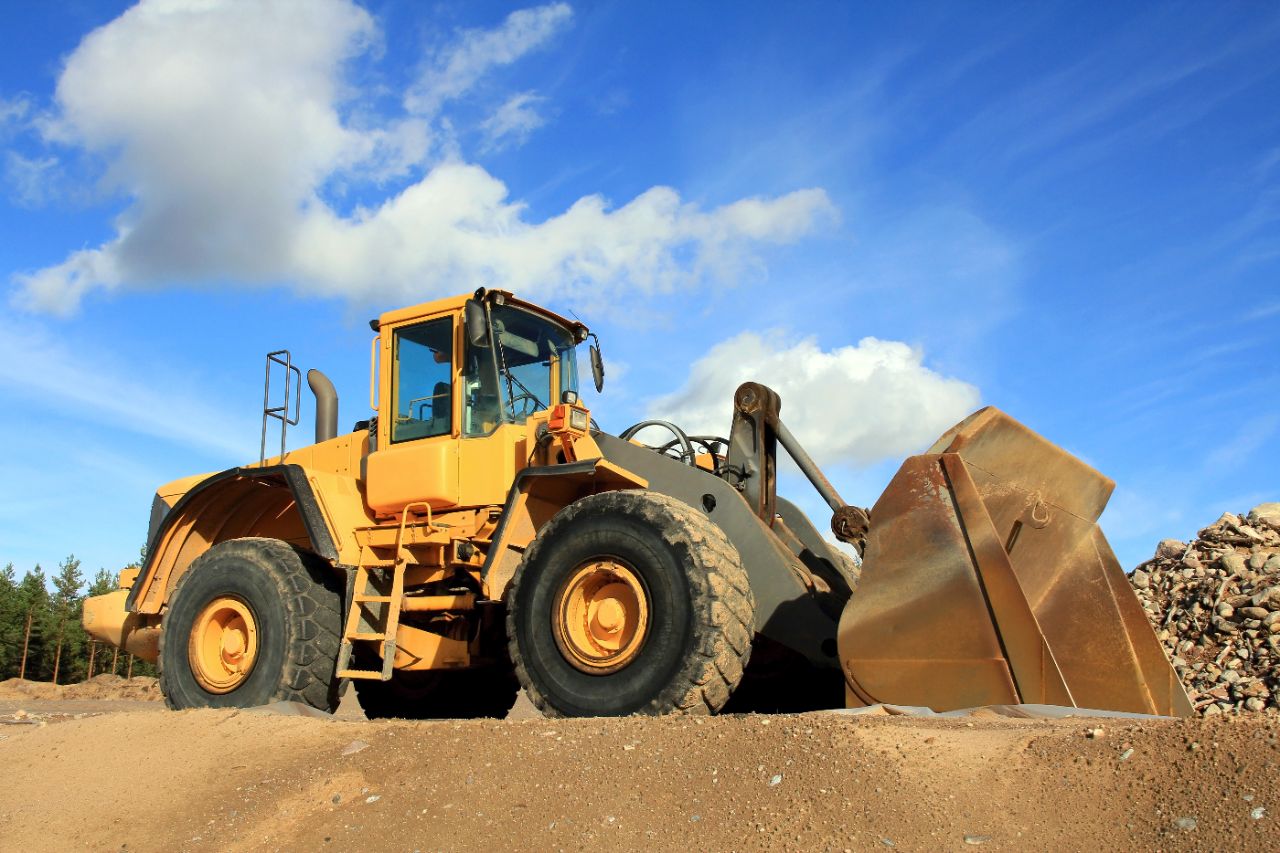 Yellow wheel loader at Sandpit against blue sky.