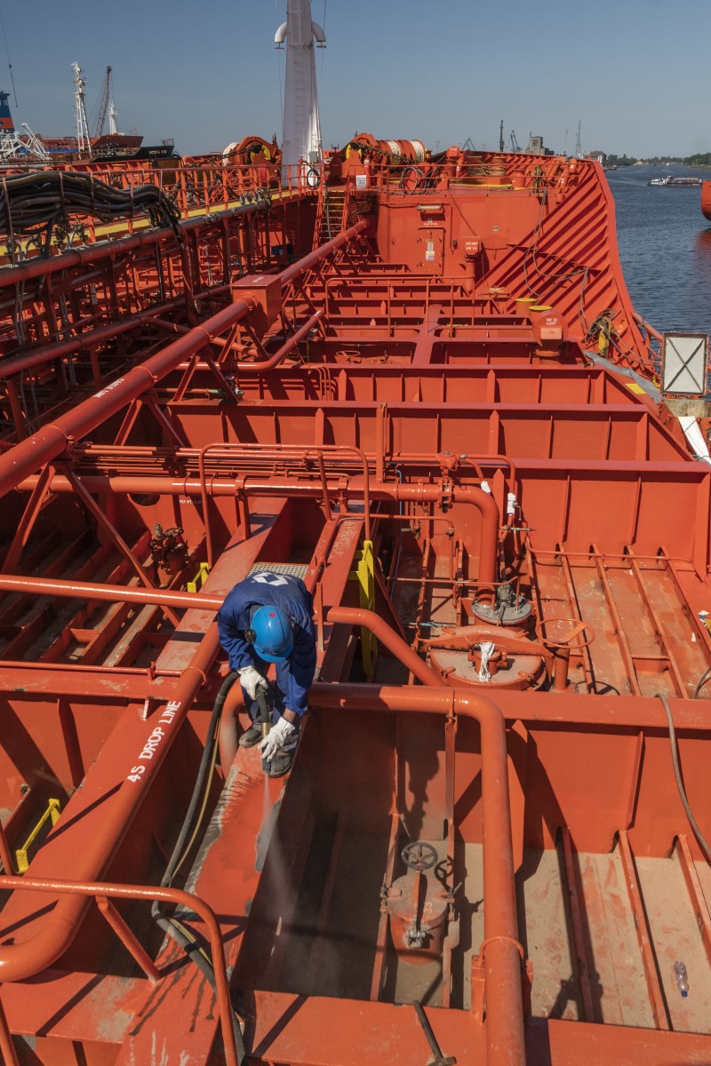 Operario aplicando chorro de vapor abrasivo en un barco