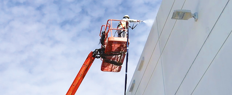 man texture spraying on an aerial work platform