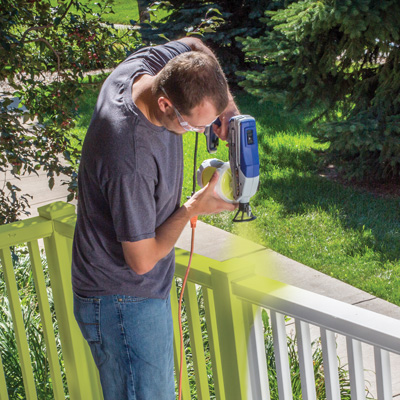 Photo d'une personne en train de peindre des balustrades avec un pulvérisateur airless