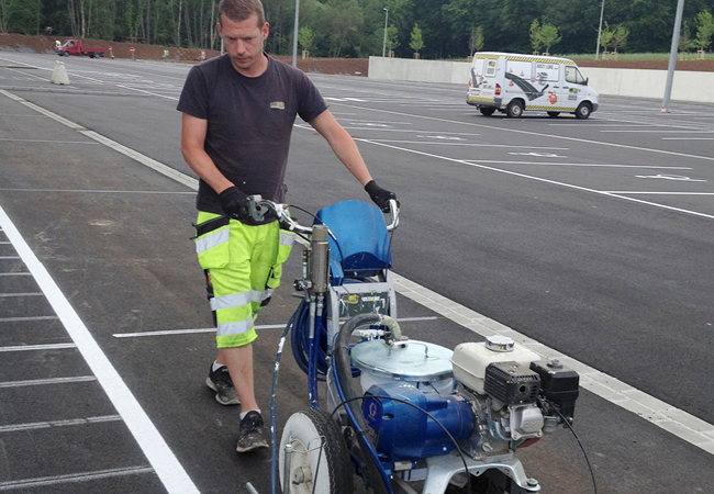 homme pulvérisant des lignes nettes sur la chaussée