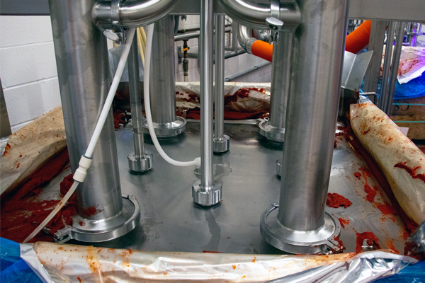Sistema de evacuación de contenedores SaniForce® con cuatro bombas de pistón para descargar pasta de tomate