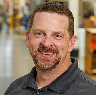 Bill Heuer smiles while in a factory that uses painting robots.