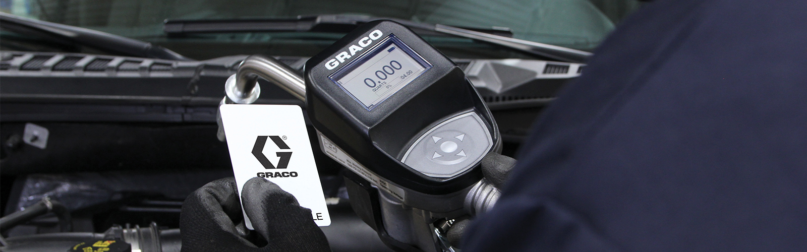 Technician holding Pulse FC Fluid Control oil dispense meter and card over truck engine