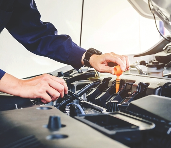 Automotive technician checking engine fluid dipstick