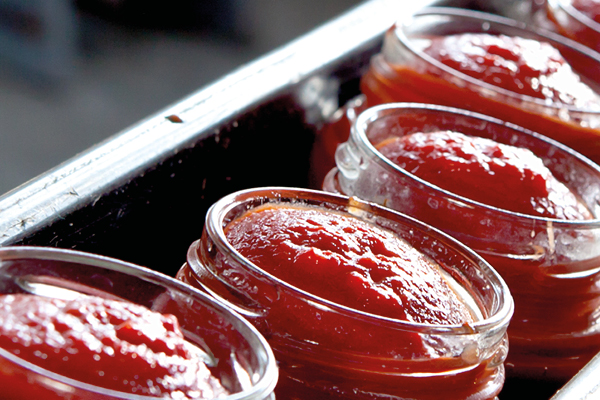 Photo de pots de sauce tomate fabriqués et remplis dans une usine utilisant les dépoteurs SaniForce de Graco pour le pompage de matériaux quasi-solides pour éviter la contamination des matériaux.