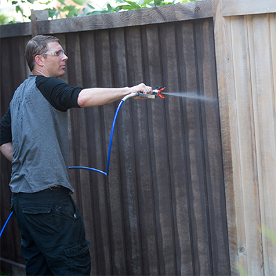 Man spraying paint on a fence