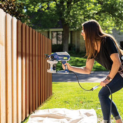 Man spraying paint on a fence