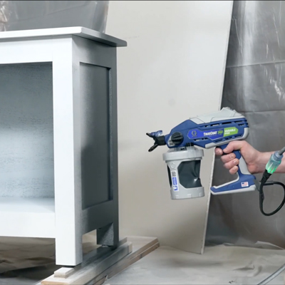 Photo of a woman using a paint sprayer to pain furnitures (peindre des meubles is the keyword)